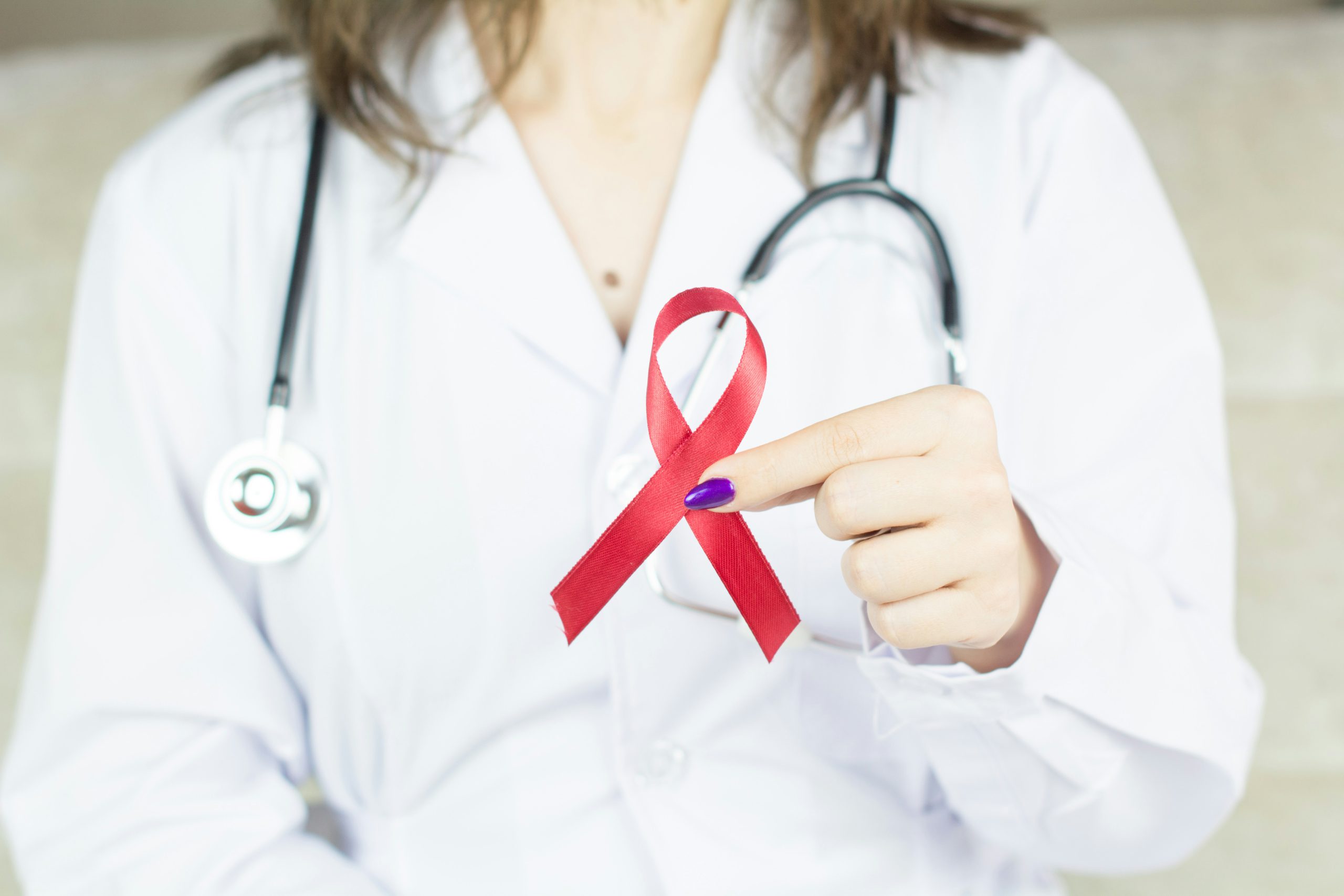 A close up of a doctor holding up a red ribbon representing HIV care offered by FAHASS in Fredericksburg, VA