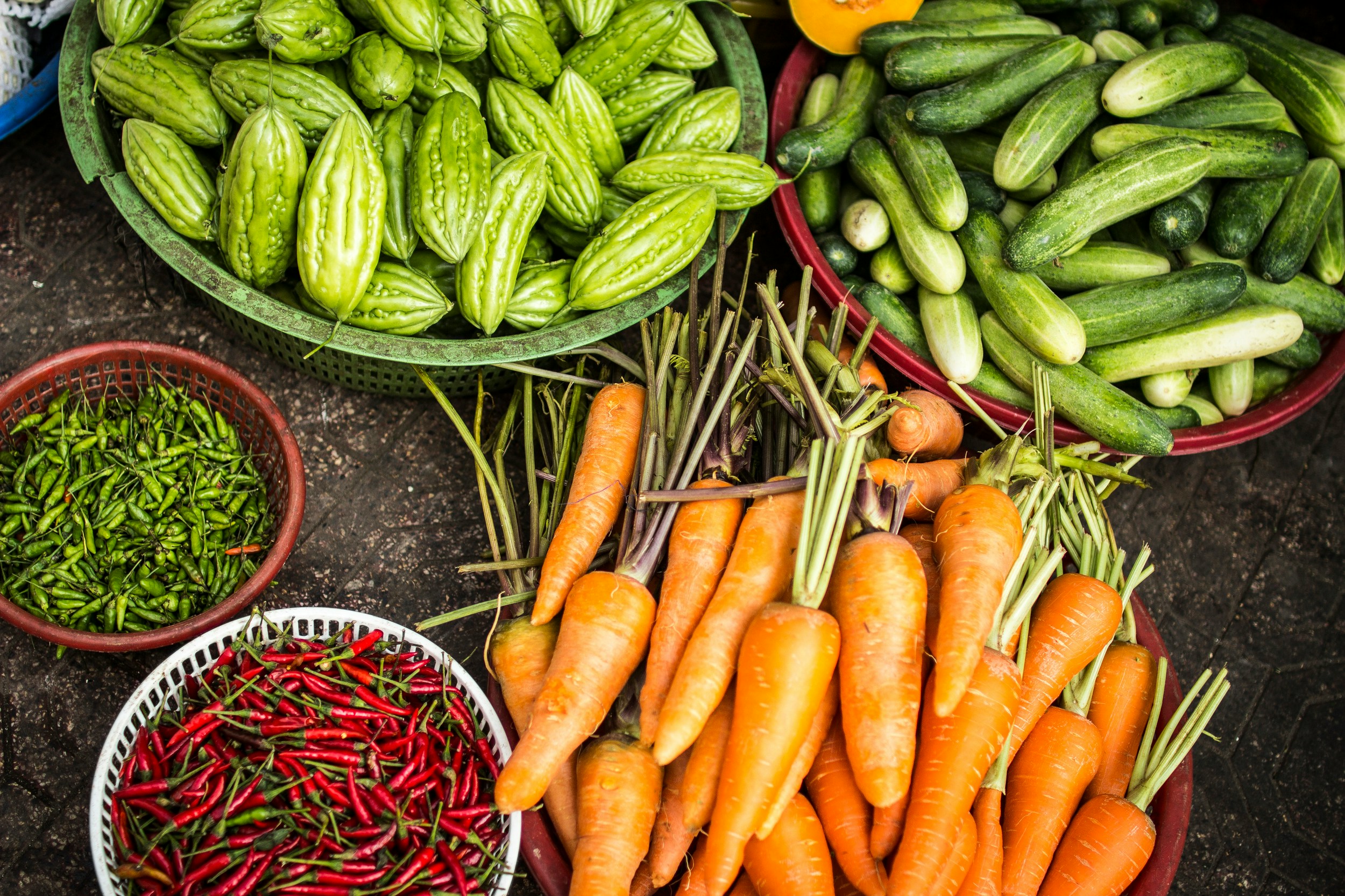 A collection of healthy vegetables like carrots, cucumbers, and red hot peppers, representing emergency food and fuel assistance, a sub service of HIV care provided by FAHASS.