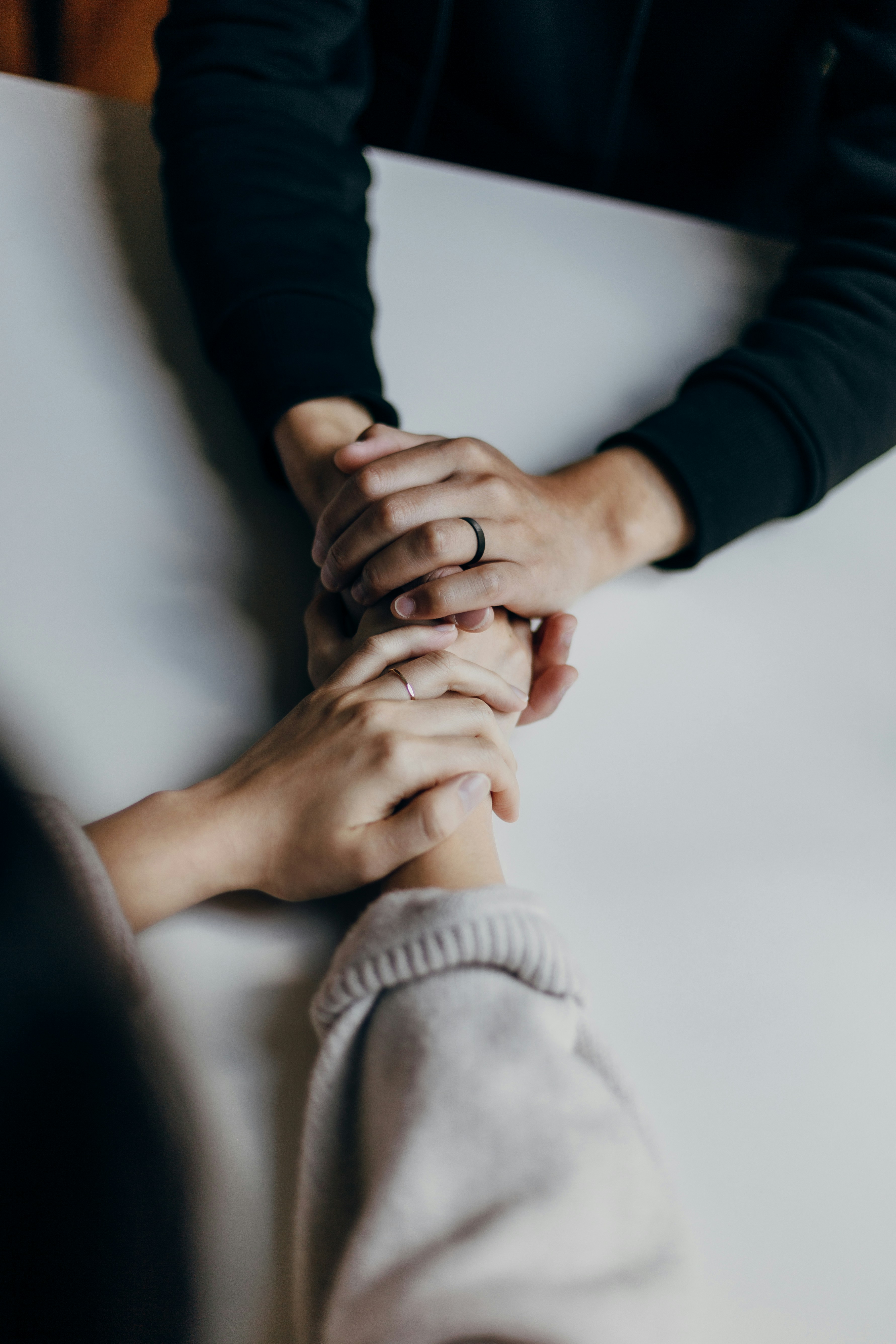 Close-up of two individuals holding hands in a show of support, symbolizing the compassionate care and mental health services at Mosaic Care Center.