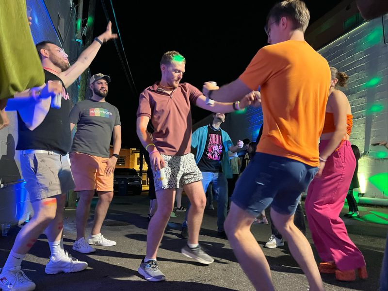 Group of diverse friends enjoying the Neon Nights event at Curitiba Art Cafe, hosted by FAHASS’ Pride Center FXBG.