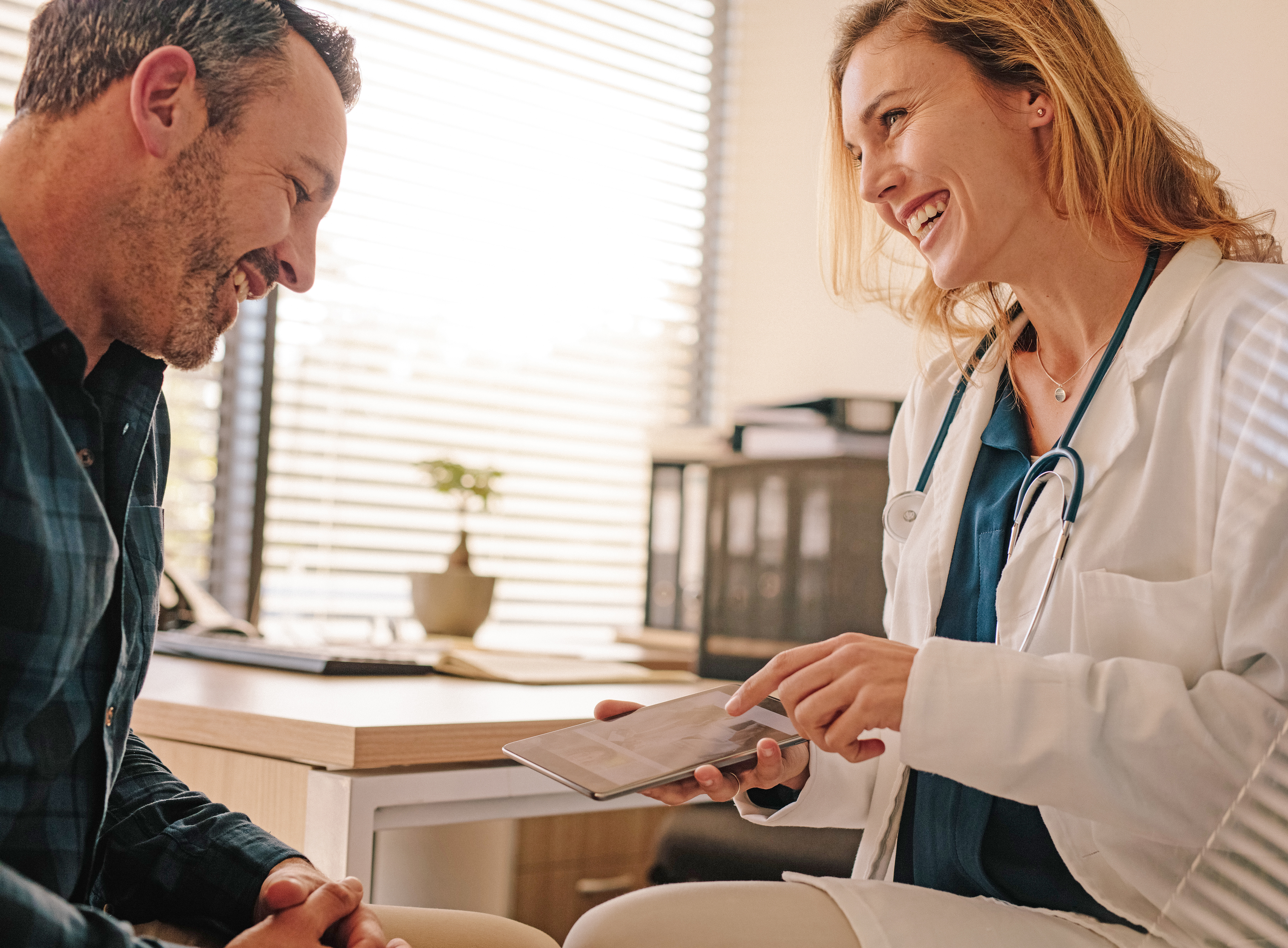 A female doctor interacting with a male patient using a tablet representing outpatient healthcare, a service offered by Mosaic Care Center in Fredericksburg, VA.