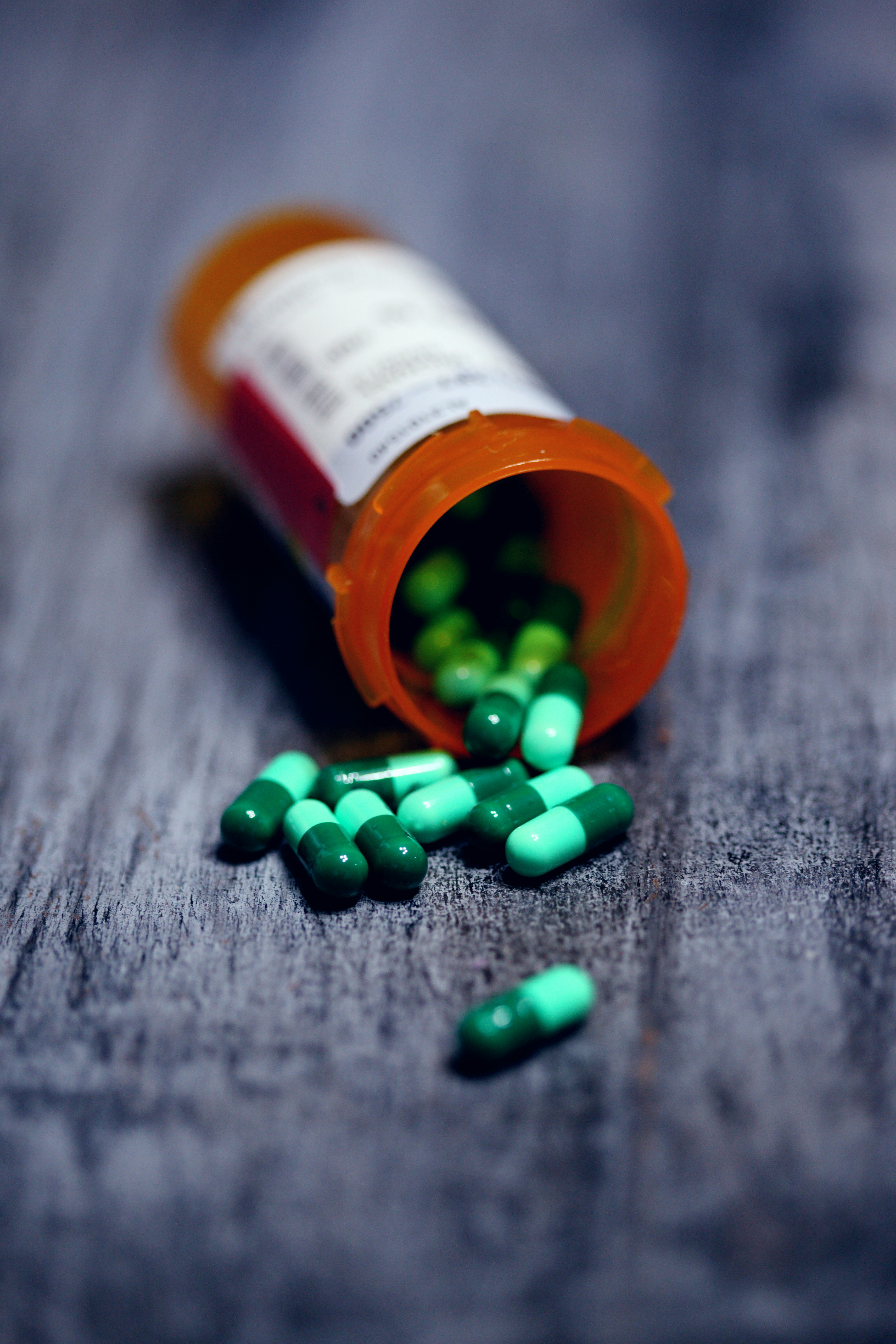 A prescription bottle spilling green and blue pills, representing access to prescription medications at Mosaic Care Center's 340B mail order pharmacy program.