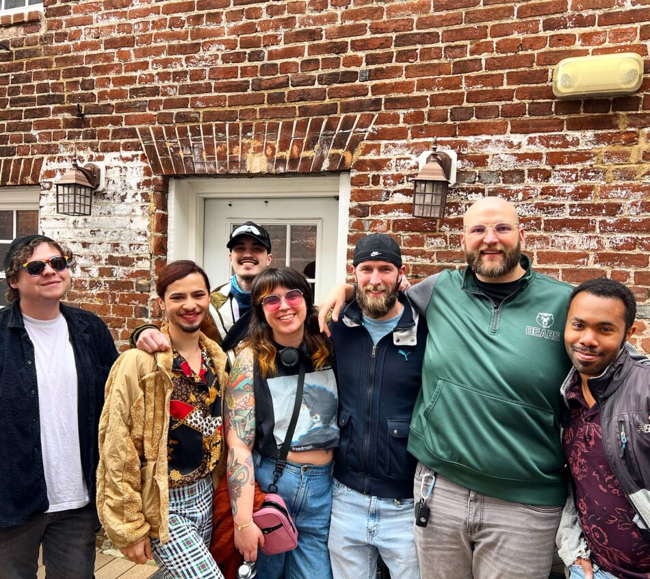 Lively gathering at the Queer Connection Coffee Social, hosted by FAHASS' Pride Center and Curitiba Art Cafe in Fredericksburg, VA, with diverse individuals on an outdoor patio.