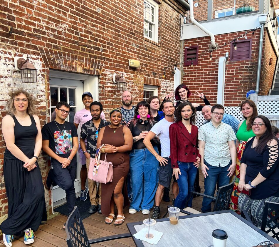 Lively gathering at the Queer Connection Coffee Social, hosted by FAHASS' Pride Center and Curitiba Art Cafe in Fredericksburg, VA, with diverse individuals on an outdoor patio.