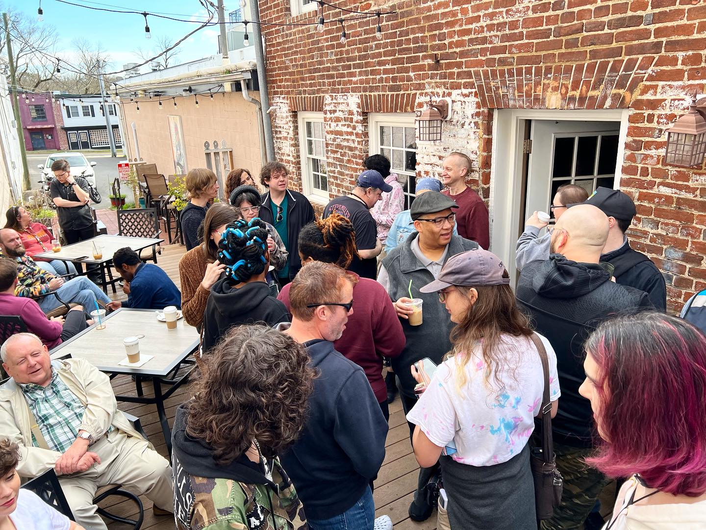 A group of diverse friends socializing at Curitiba Art Cafe in Fredericksburg, VA as part of the Queer Connections Program by Pride Center FXBG.